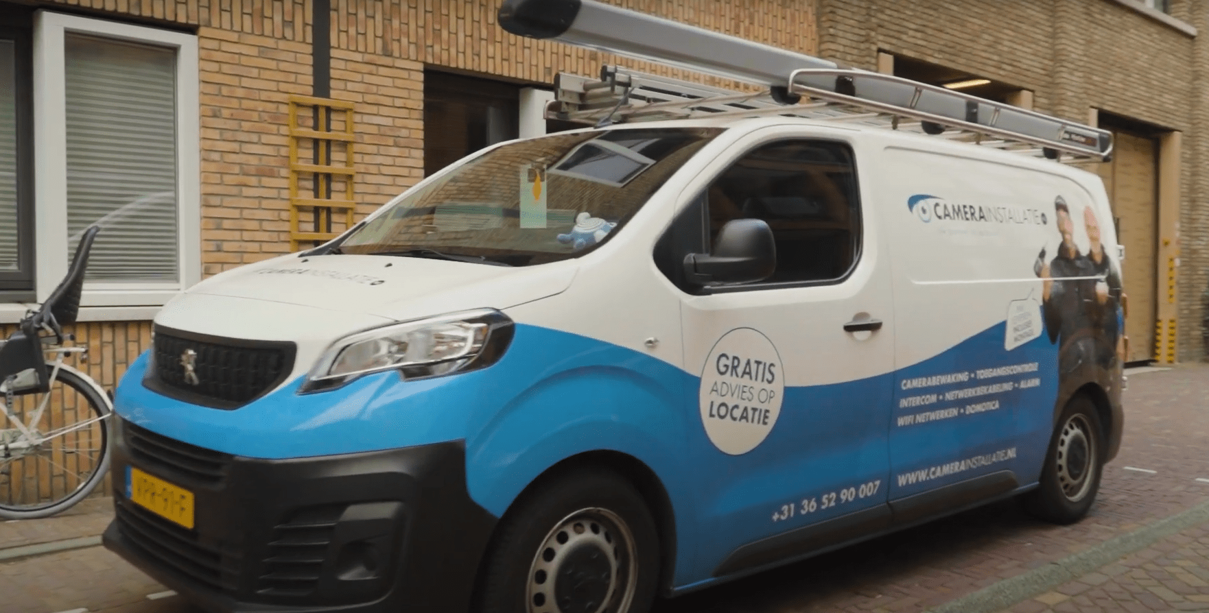 De werkbus van CameraInstallatie staat voor het complex in Haarlem