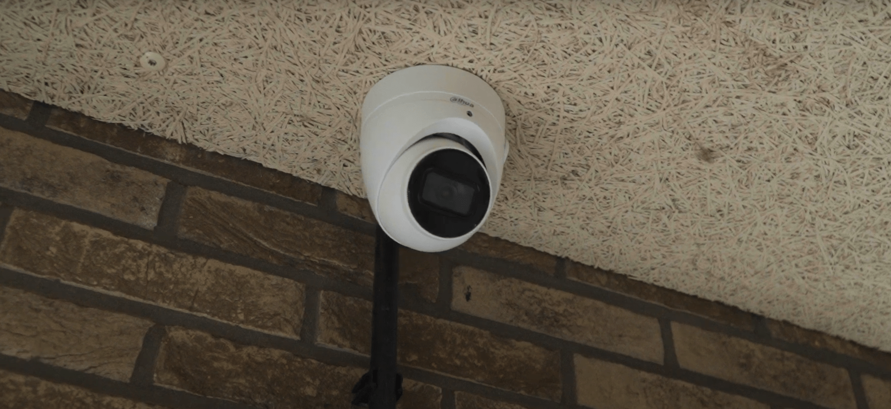 Camera aan de bakstenen buitengevel, gericht op de buitenruimte van het complex