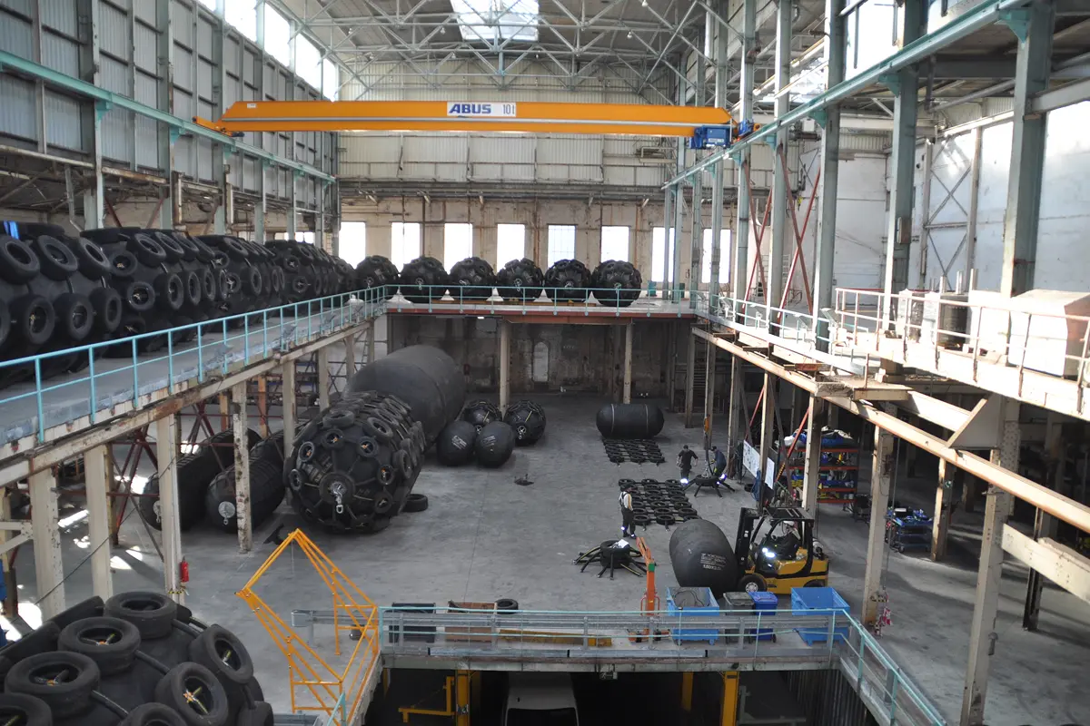 Grote industriehal met een bovenloopkraan, stellingen en een heftruck