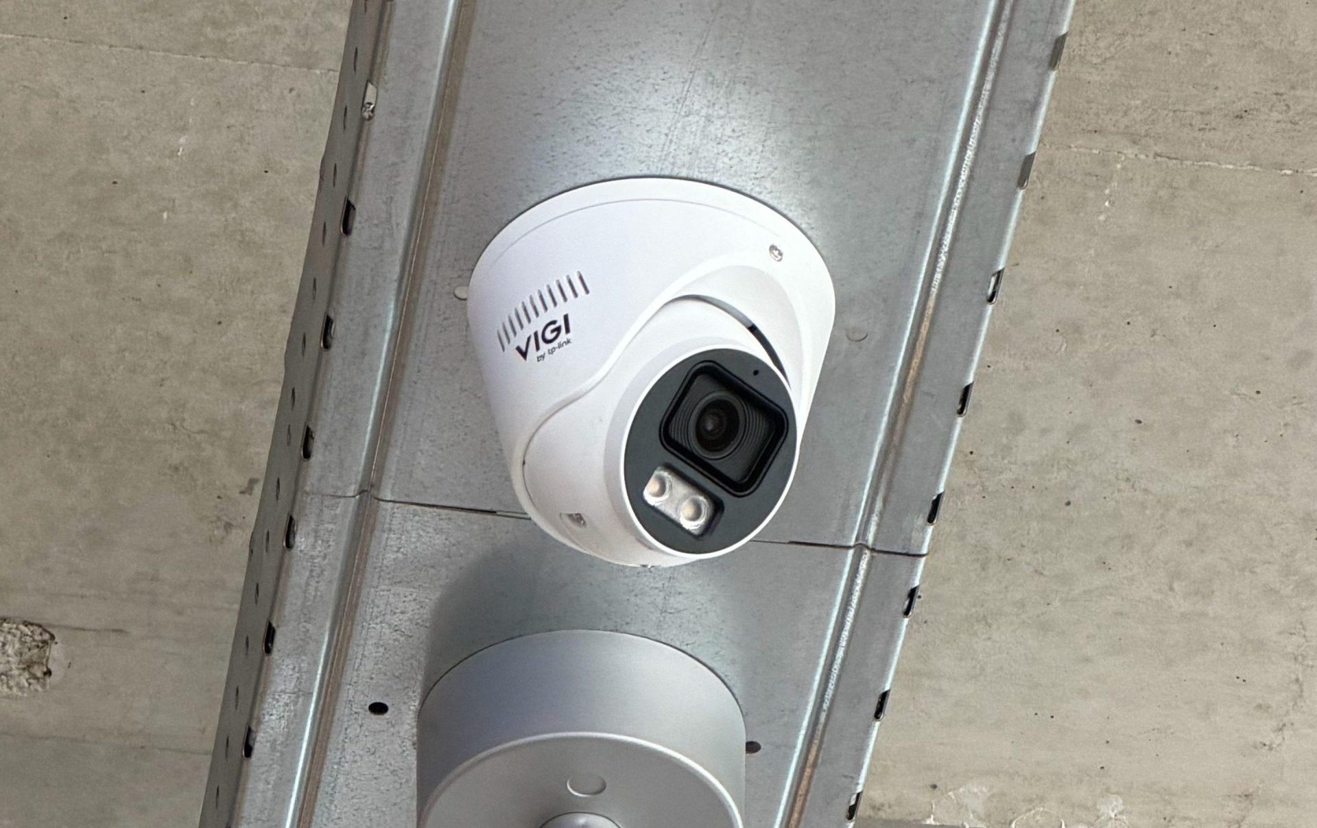 Twee VIGI by TP-Link turretcamera's netjes weggewerkt in een metalen kabelgoot tegen een betonnen plafond