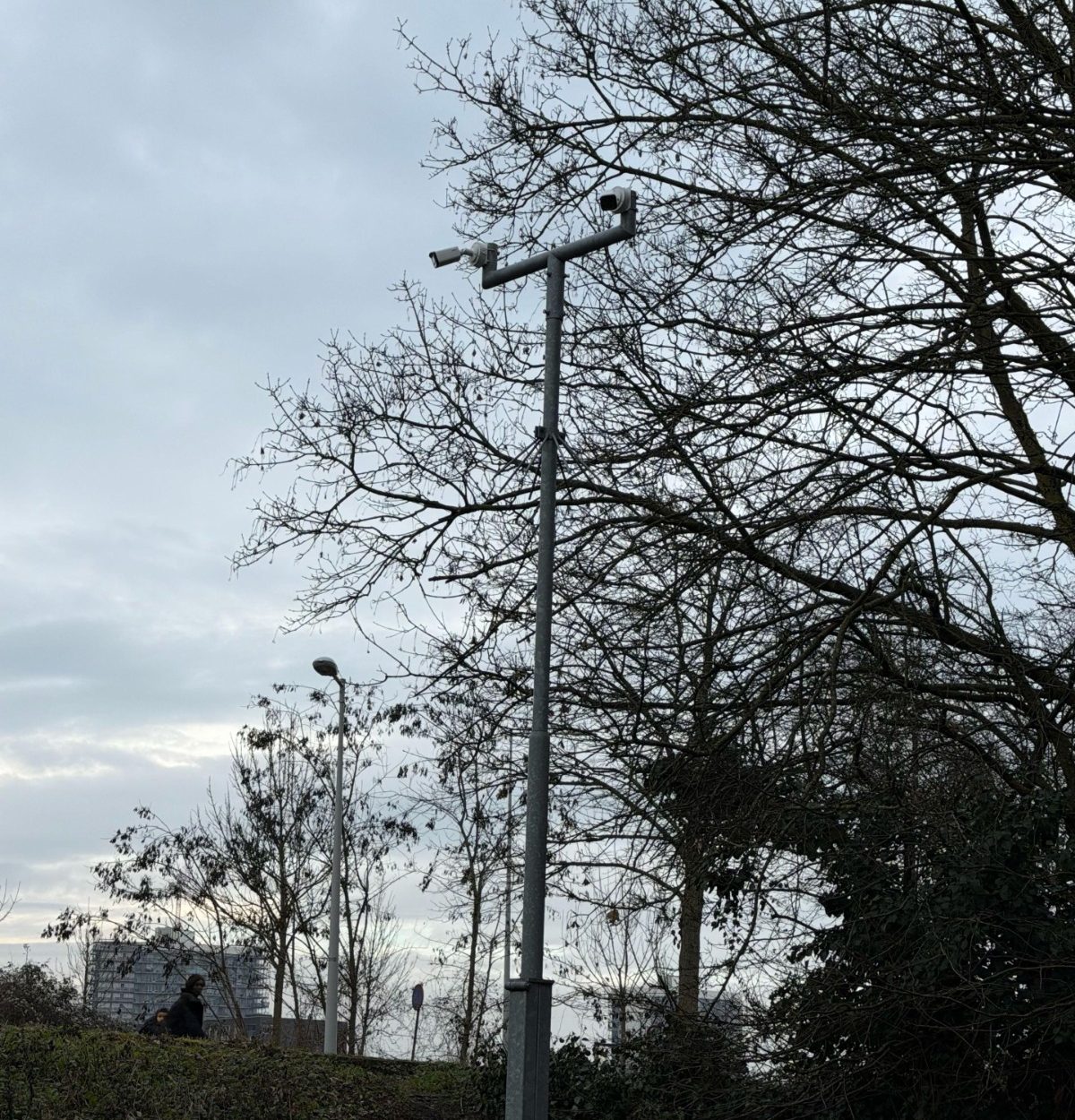 Bewakingscamera op een hoge mast houdt het gemeenschappelijke buitenterrein van een appartementencomplex in de gaten, met woonblokken op de achtergrond
