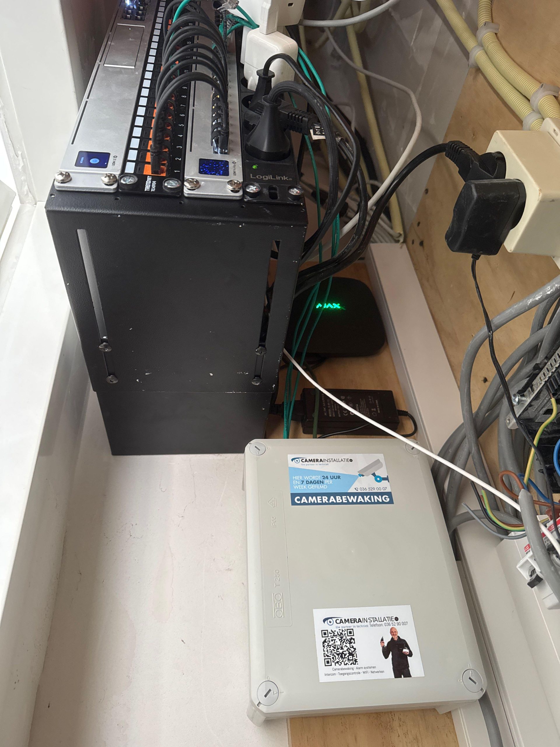 Netwerkkast met patchpaneel, PoE-switch en een aansluitkast met sticker van CameraInstallatie