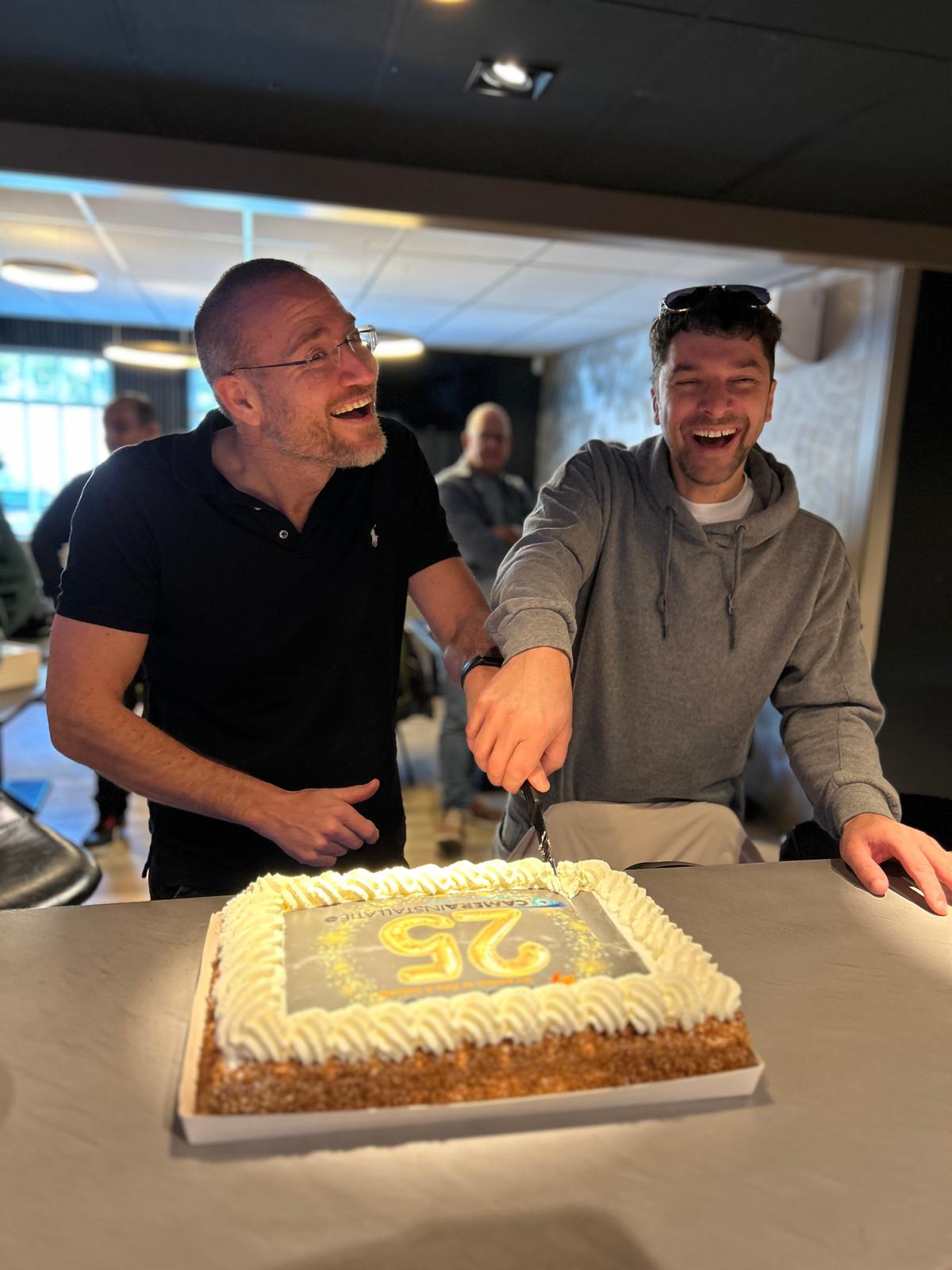 Oprichters Marc en John snijden lachend de taart aan voor het 25-jarig bestaan van CameraInstallatie