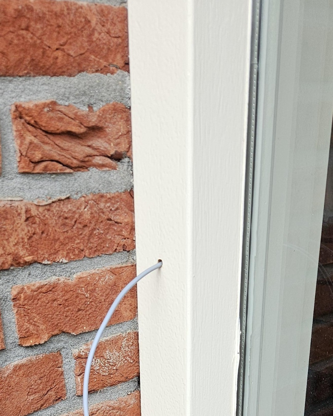 Onze monteur trekt netjes de kabel voor de Ajax DoorBell door de gevel