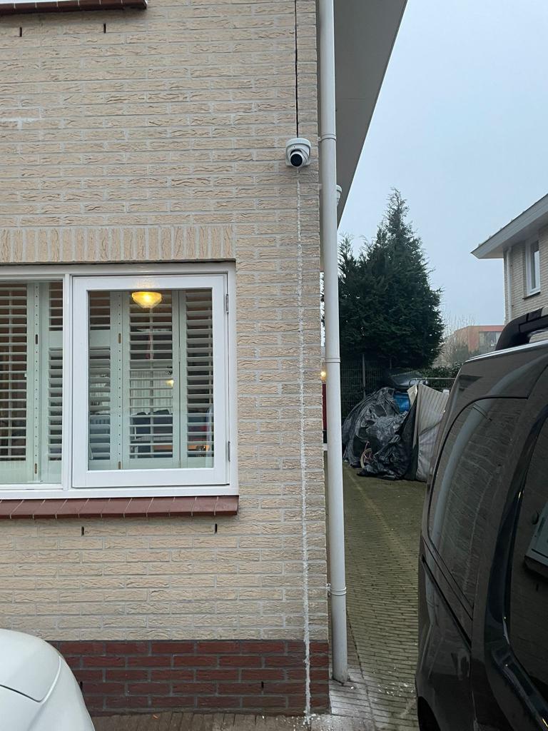 Camera aan de zijgevel van een woning, met zicht op het pad ernaast