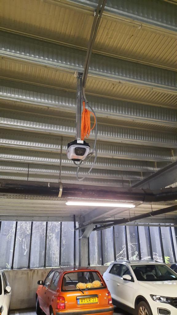 Beveiligingscamera aan het plafond van een parkeergarage met auto's