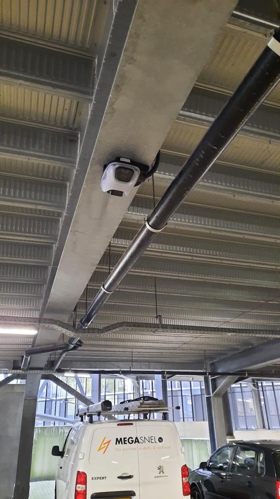 Camera aan een betonnen balk boven de parkeerplaatsen van een overdekte parkeerruimte