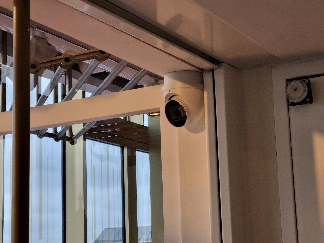 Witte turret-camera bij de glazen entreepui van een winkel