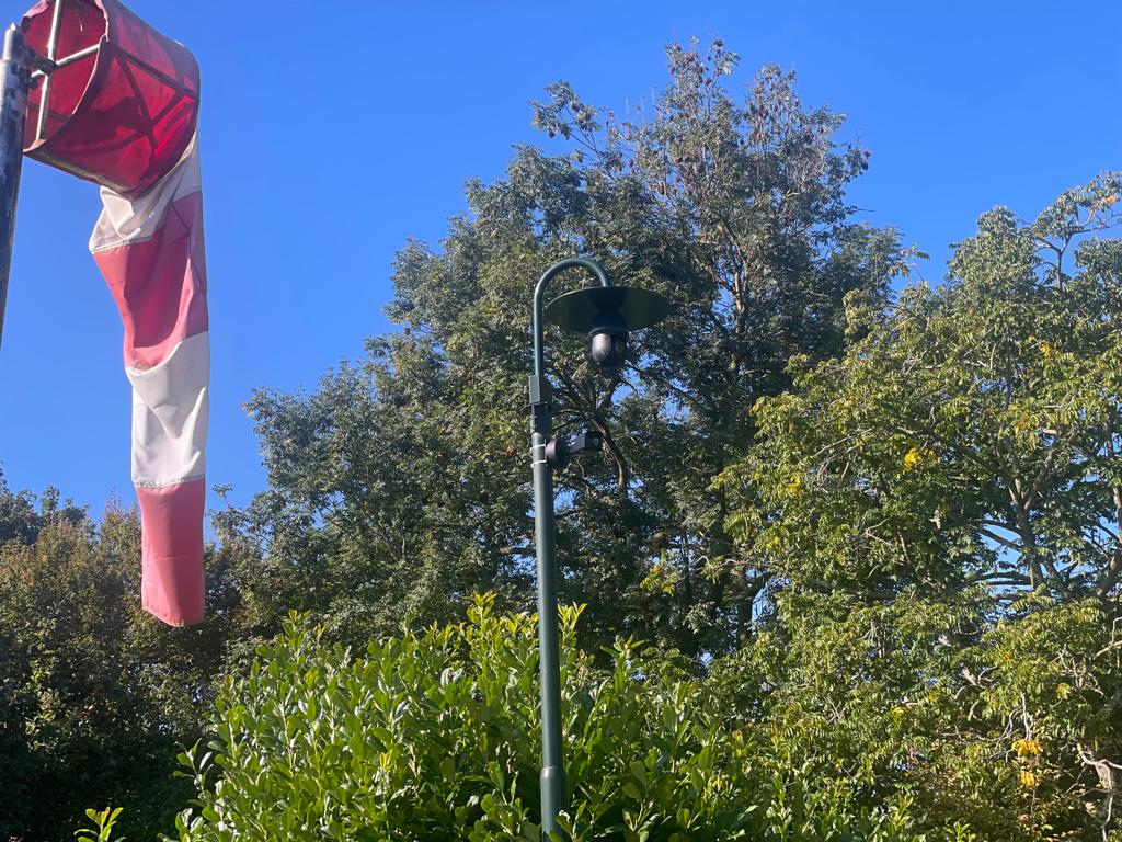 Camera hoog op een paal naast de windzak op het terrein