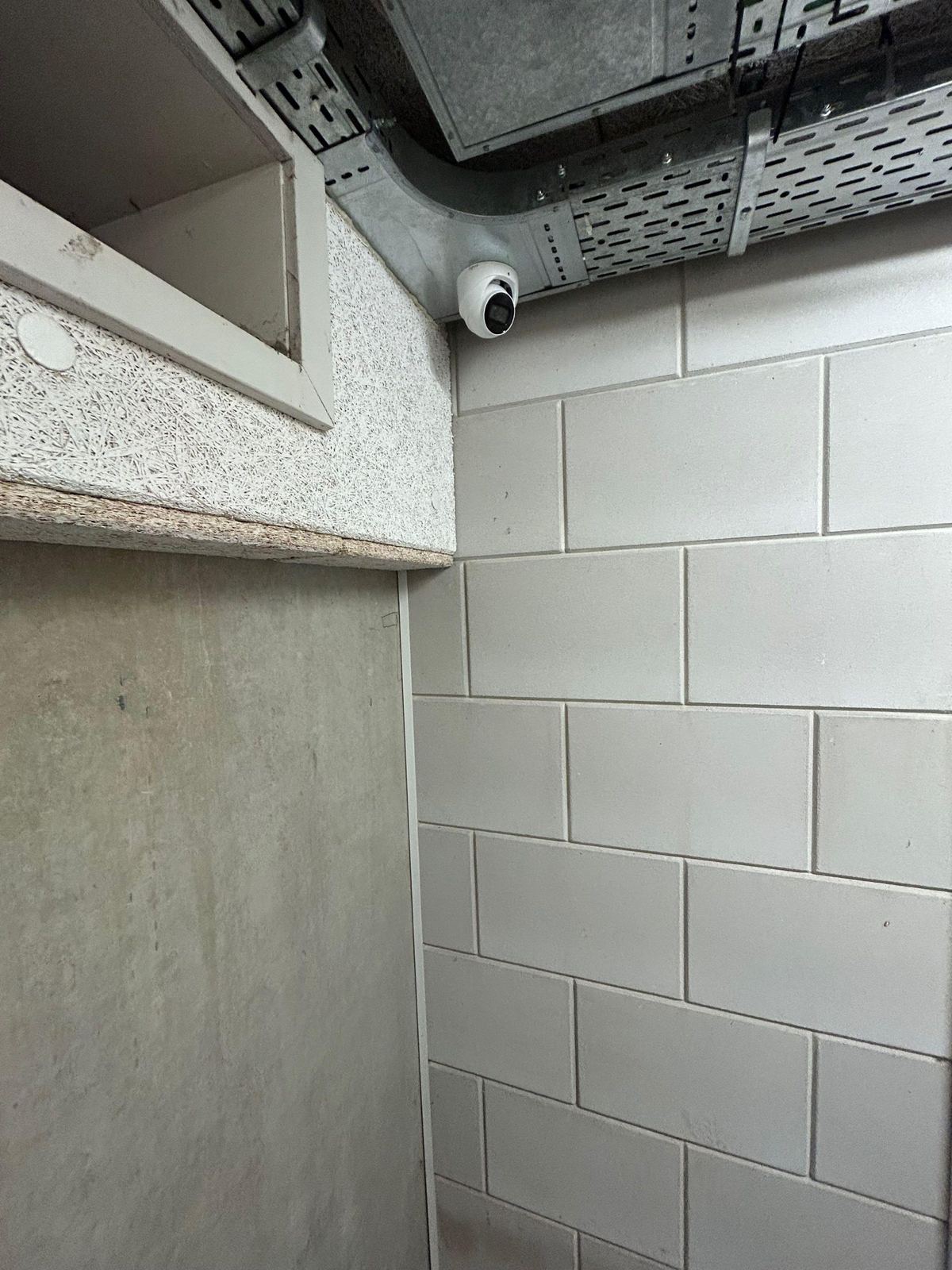 Witte camera in de hoek van een gang met betonblokken in een openbaar gebouw
