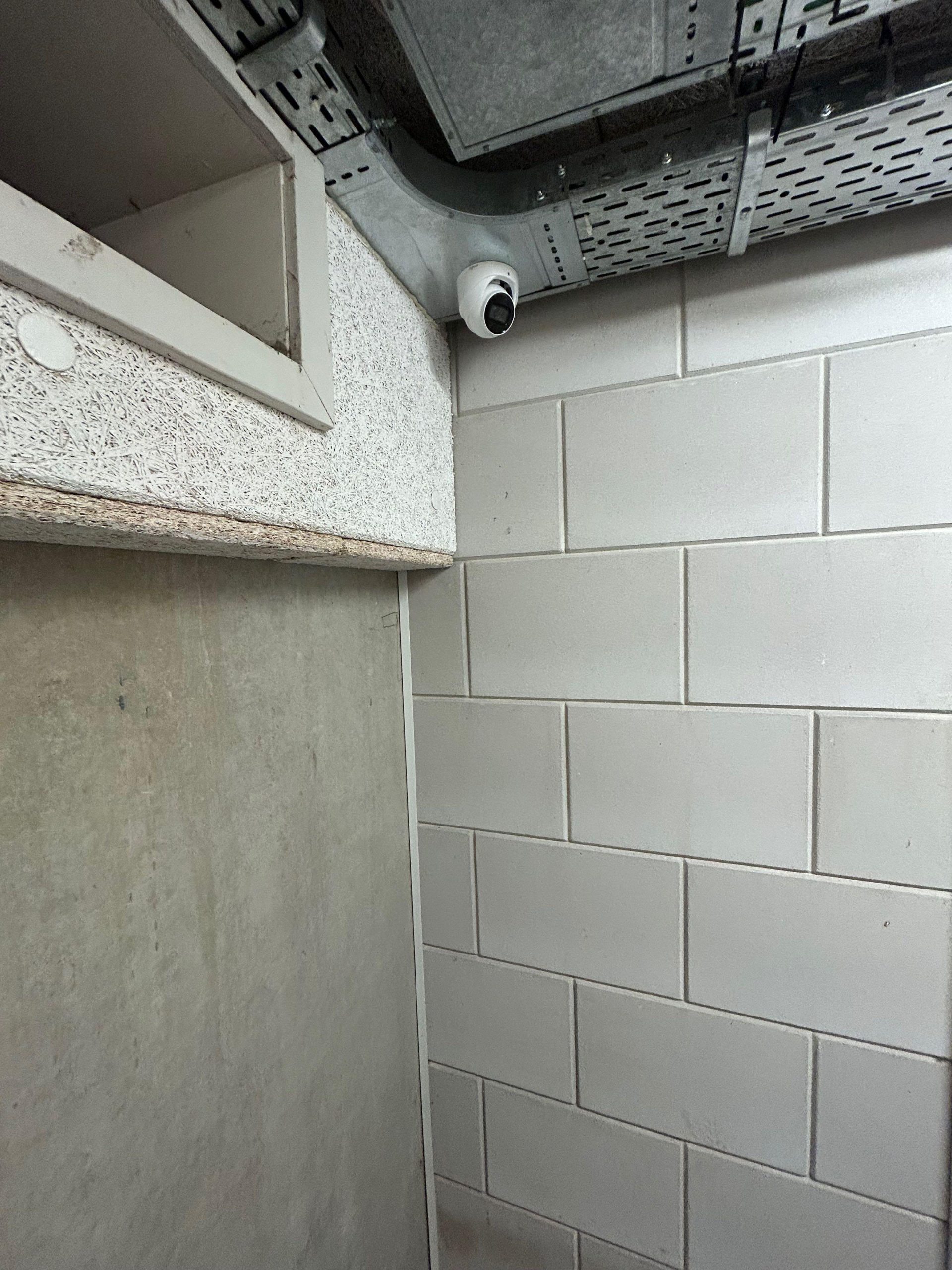 Witte camera in de hoek van een gang met betonblokken in een openbaar gebouw