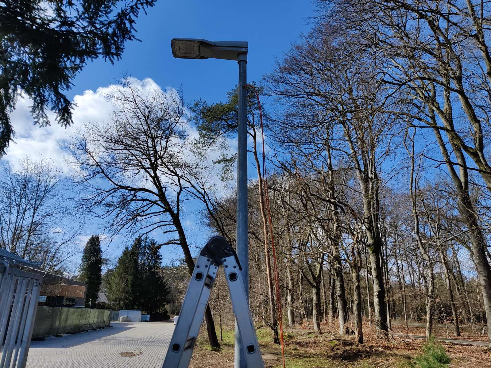 Beveiligingscamera hoog op een bestaande lichtmast langs de terreingrens