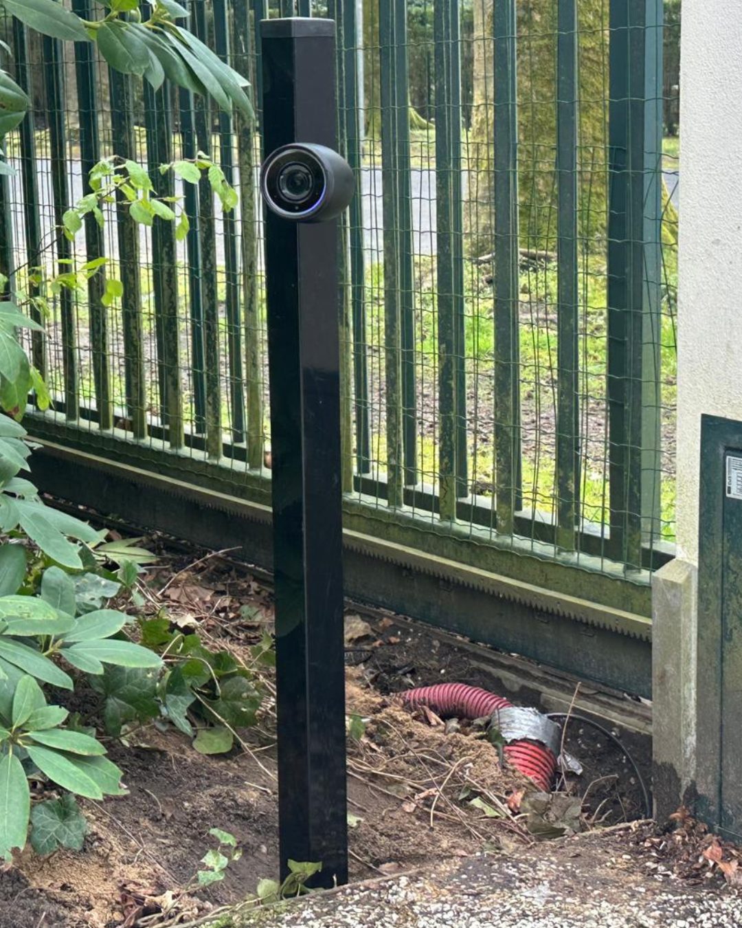 Camera op een zwarte paal langs het hekwerk, met de kabelbuis nog open in de grond