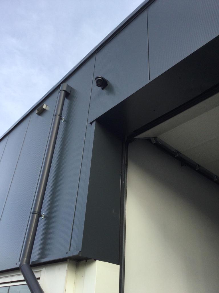 Twee camera&rsquo;s onder het overstek van een donker pand