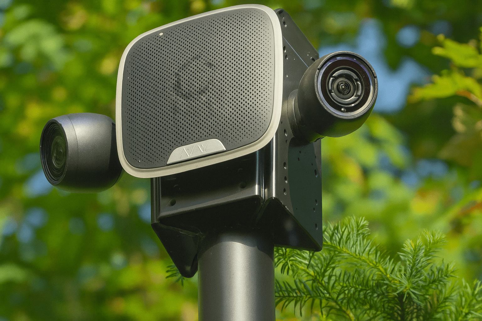 Twee camera&rsquo;s met een grote luidspreker samen op &eacute;&eacute;n paal langs een terrein