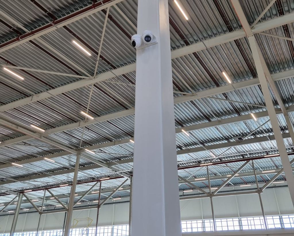 Twee witte turretcameras op een stalen kolom in een bedrijfshal