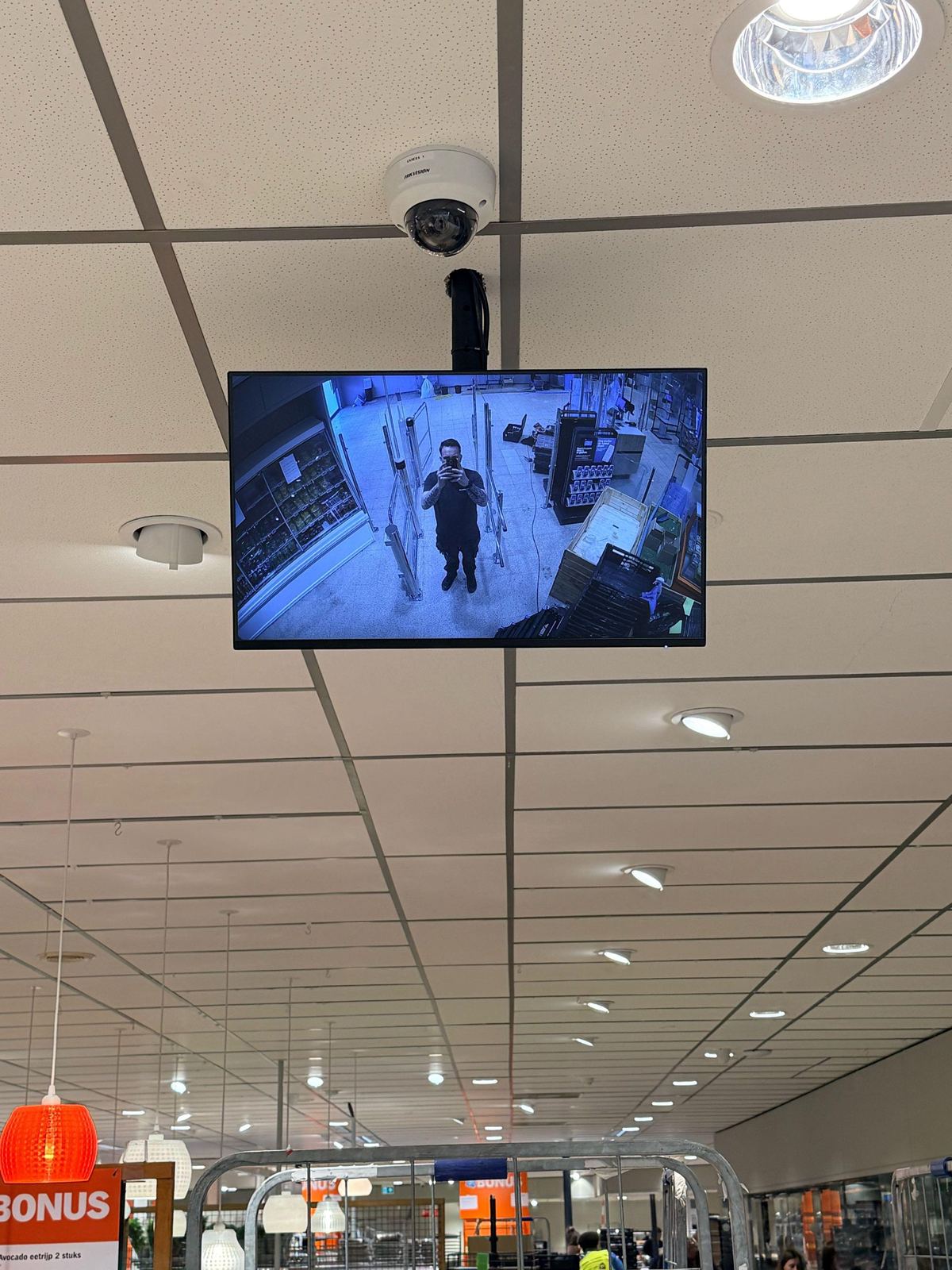 Monitor met live camerabeeld in een winkel, waarop bezoekers herkenbaar in beeld staan