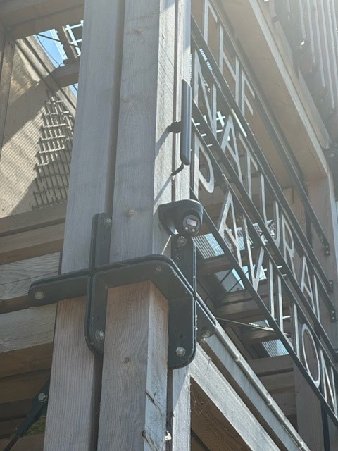 Detail van een Dahua-camera op een zwarte wandbeugel, vlak gemonteerd tegen een houten geveldeel