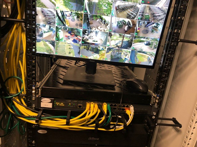 Recorder van CameraInstallatie met netwerkswitch en een monitor met live camerabeelden, netjes weggewerkt in een kast