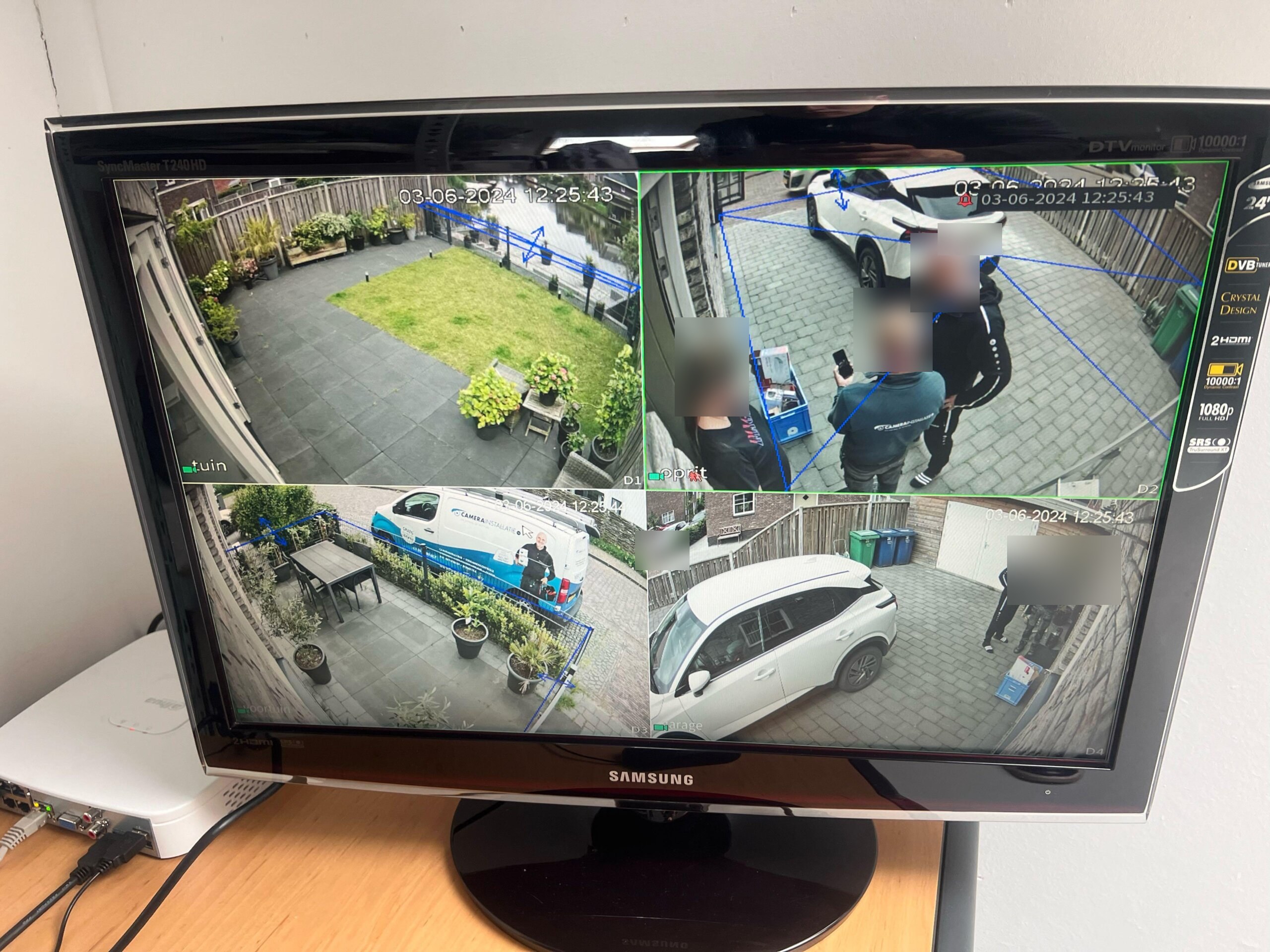 Monitor met vier live camerabeelden van de woning en blauwe lijnen die de ingestelde detectiezones aangeven