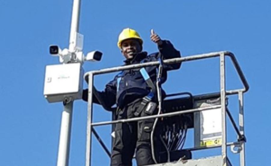 Monteur in een hoogwerkerbak naast twee camera's en een kast op een verrijdbare mast