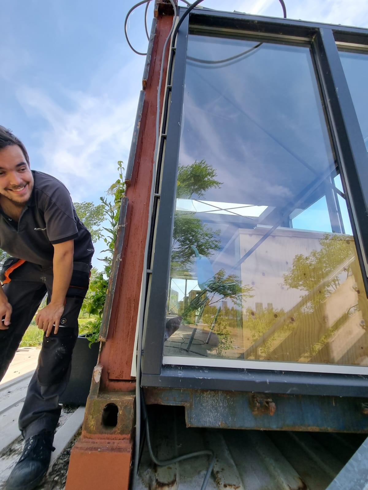 Monteur van CameraInstallatie legt bekabeling langs een glazen staalstructuur op het dak
