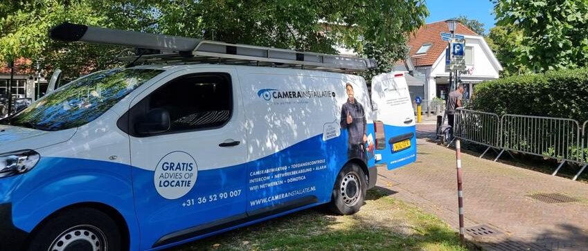 Servicebus van CameraInstallatie.nl in het centrum, geparkeerd bij dranghekken tijdens de opbouw
