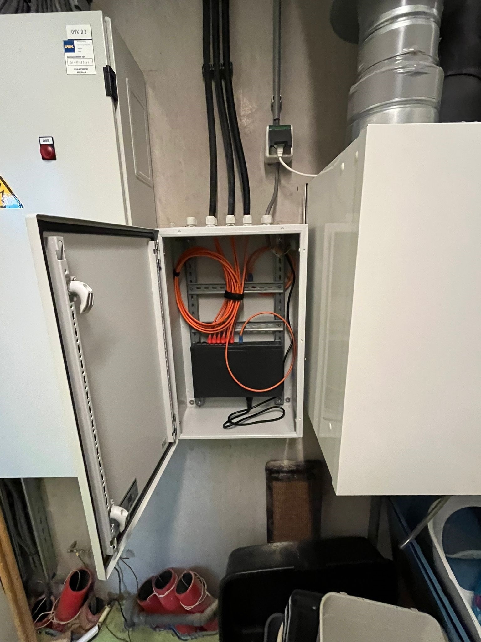 Netwerkkast met oranje patchkabels en netwerkapparatuur, netjes aangelegd door CameraInstallatie.nl