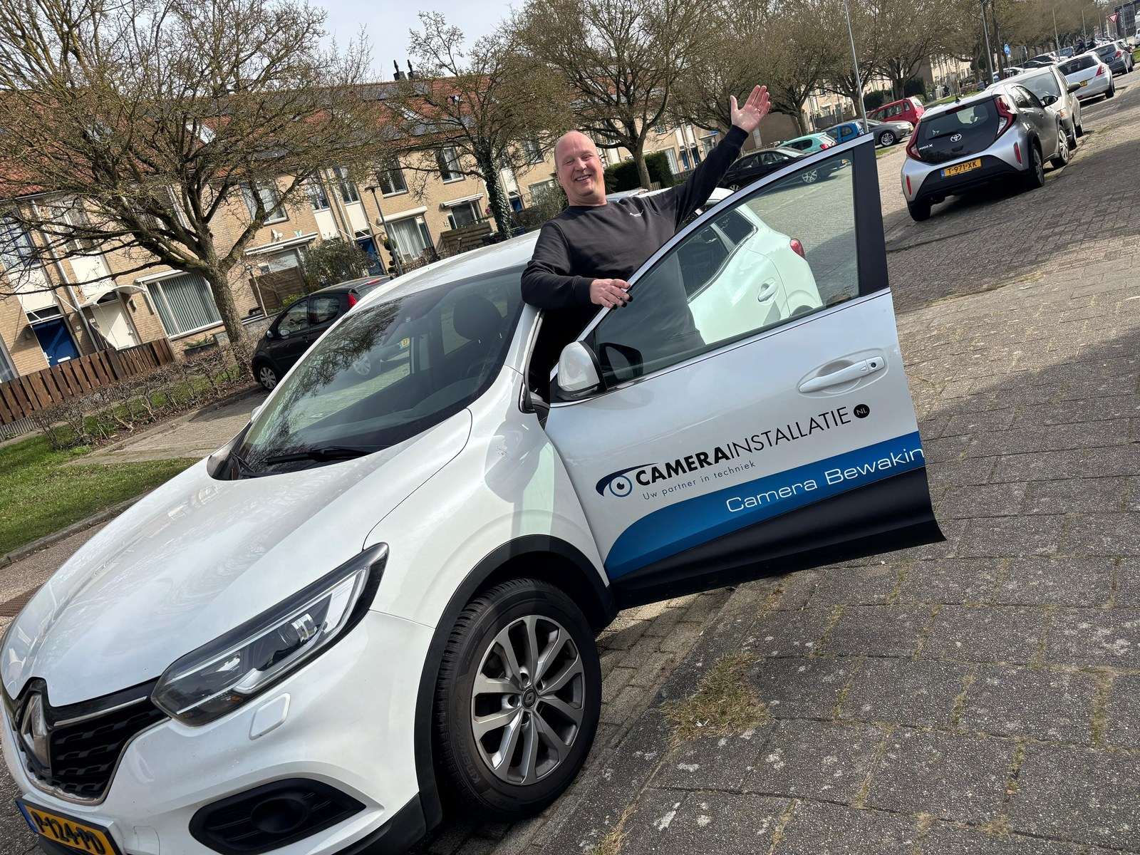 Medewerker van CameraInstallatie bij een bedrijfsauto met het logo op de zijkant