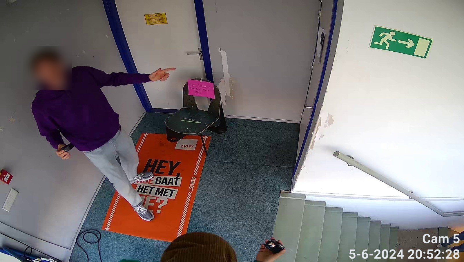 Camerabeeld van een entree waarop een persoon herkenbaar in beeld staat