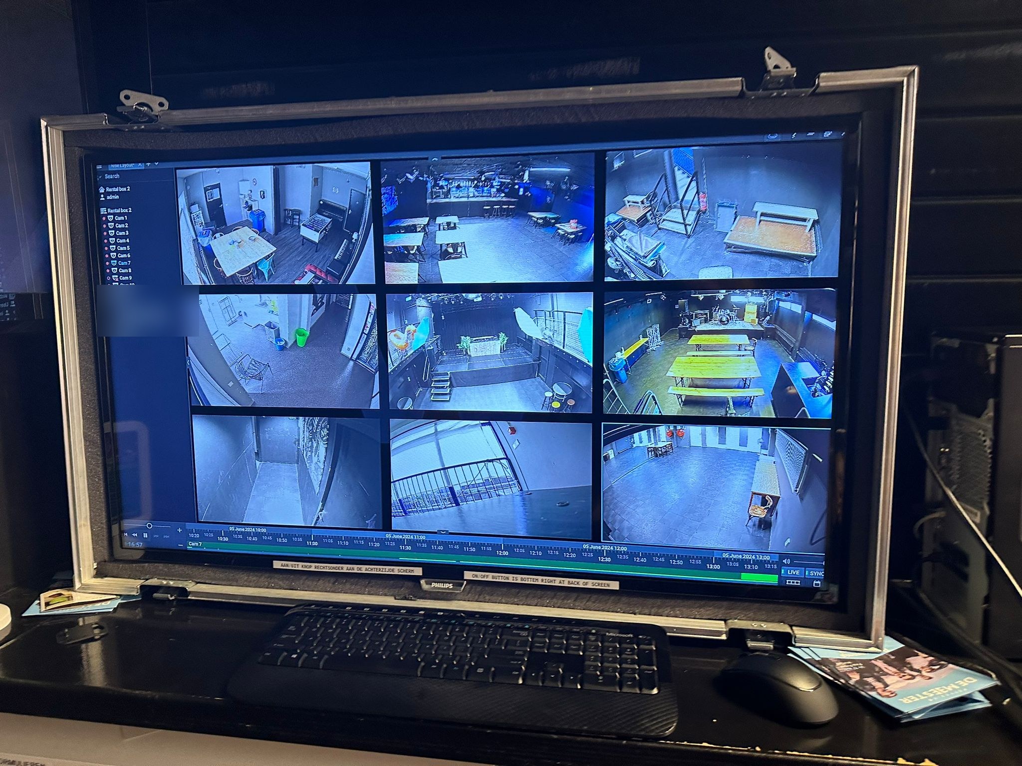 Beeldscherm op een werkplek toont de beeldsoftware met negen live camerabeelden in een raster en een tijdlijn onderaan