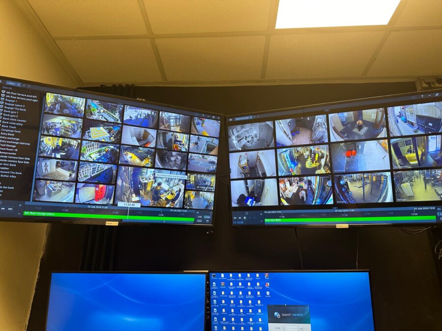 VMS-bedienbeeld met tientallen live camerabeelden naast elkaar op een monitorwand in een uitkijkruimte