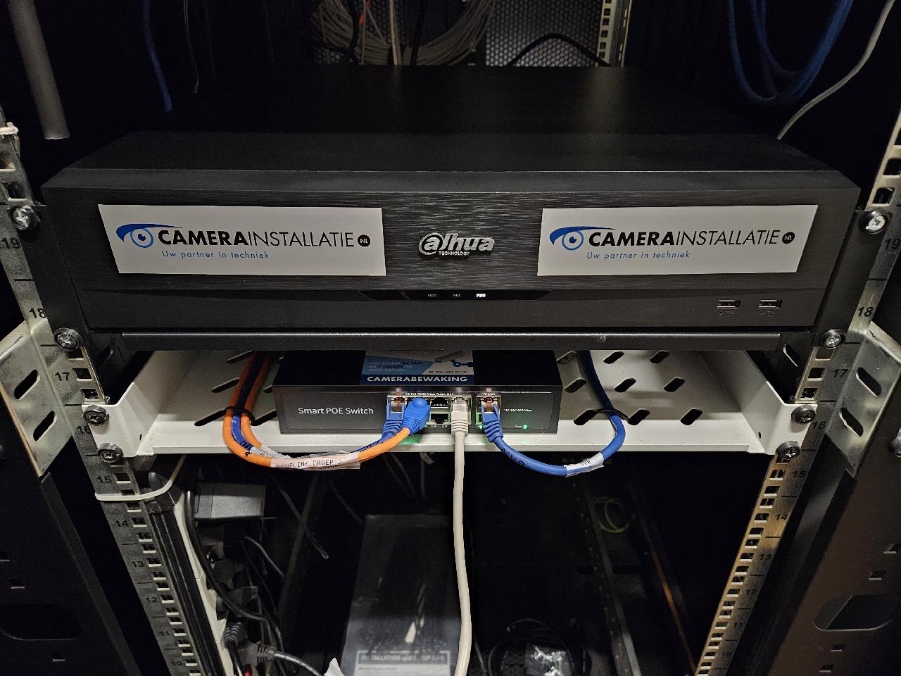 Zwarte Dahua NVR-recorder met CameraInstallatie-stickers in een netwerkrek boven een PoE-switch