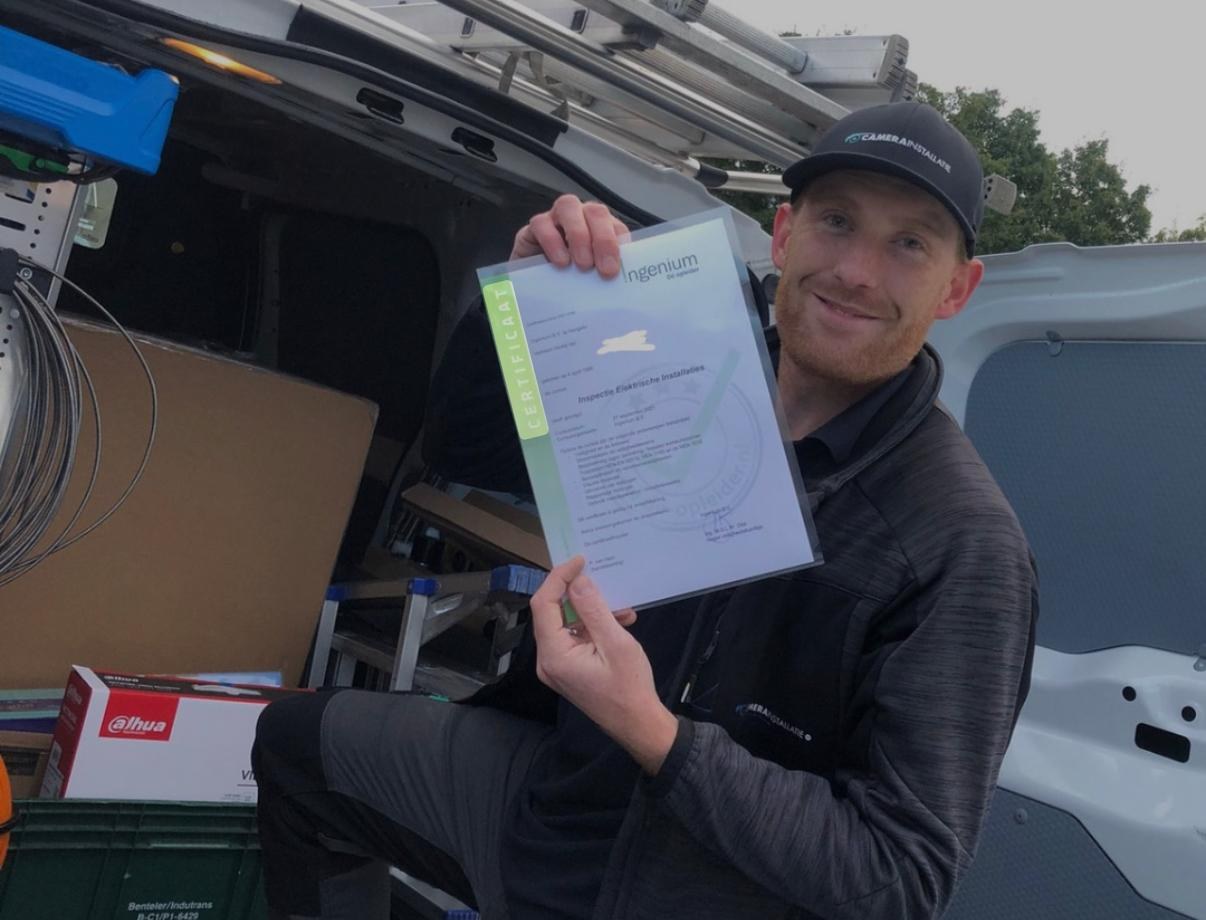 Monteur bij de open servicebus met een certificaat, naast een krat met Dahua-materiaal