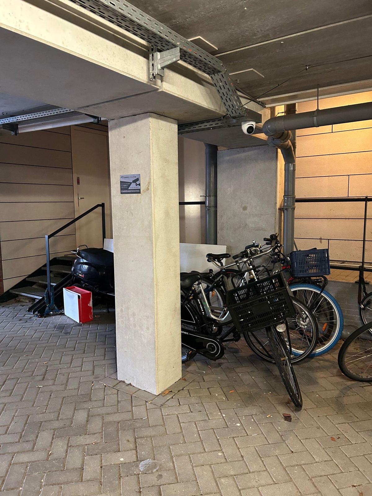 Camera aan het betonnen plafond van een overdekte doorgang met een fietsenstalling
