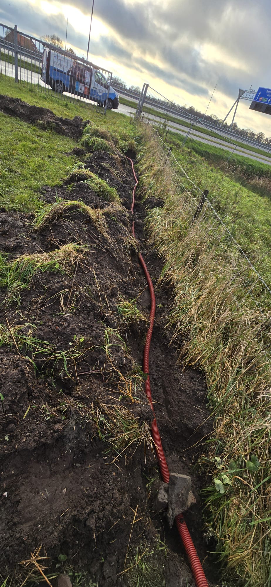 Rode kabelbuis in een gegraven sleuf langs de weg naar de cameramast