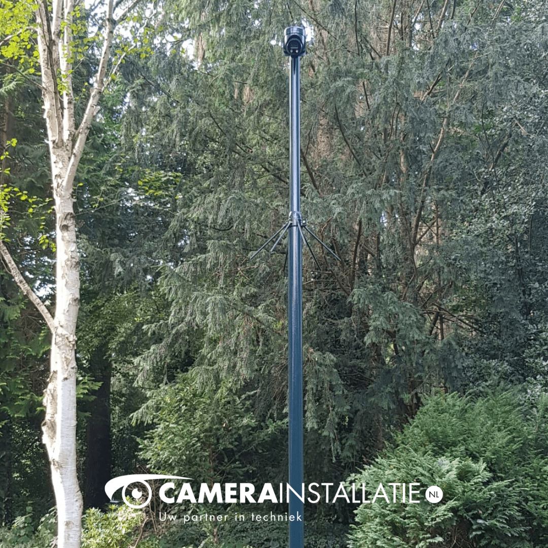 Camerapaal met bewakingscamera in een groene tuin, geplaatst door CameraInstallatie