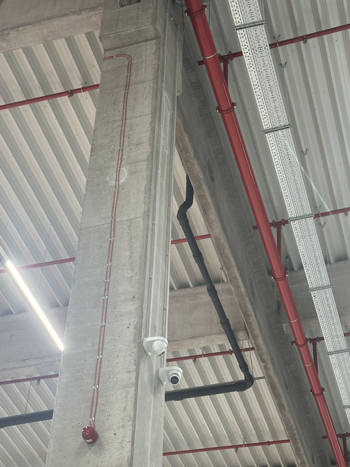 Camera hoog aan een betonkolom met zicht over een stellinggang in het magazijn