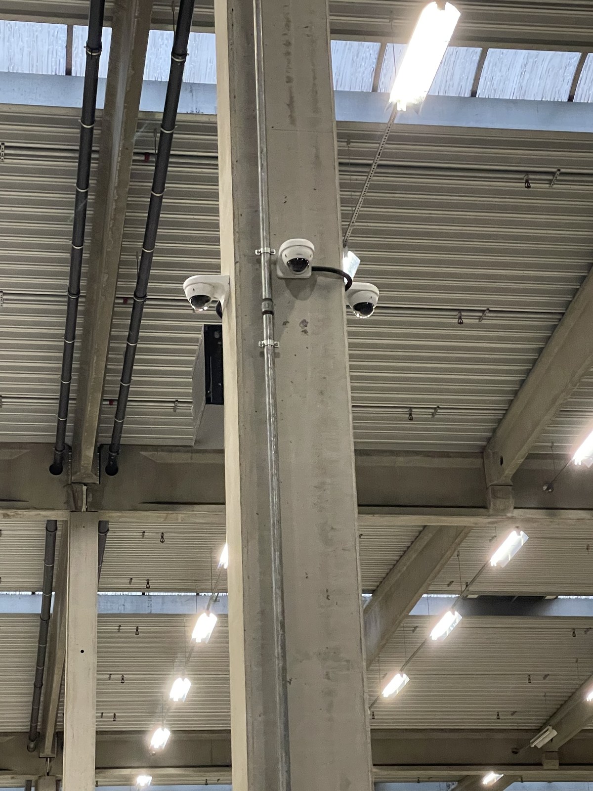 Drie dome-camera's aan een betonkolom in een groot magazijn
