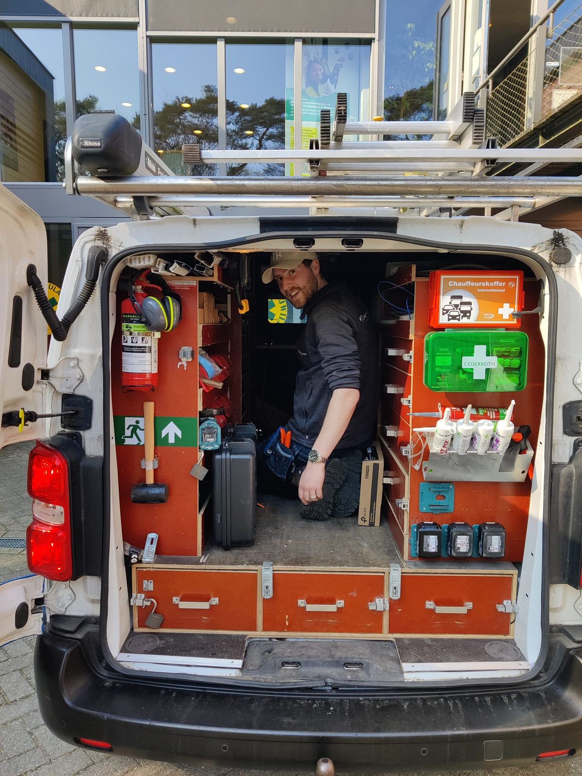 Open achterdeuren van een volledig ingerichte servicebus met gereedschap, EHBO-koffer en materiaal