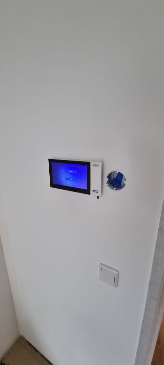 Binnenscherm van de video-intercom aan de wand, met beeld van de deur