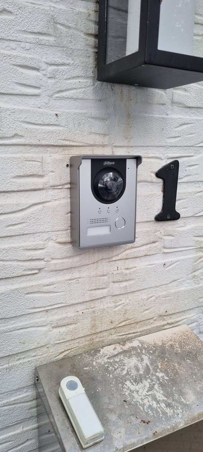 Nieuwe grijze intercompost naast het huisnummer, met de oude witte drukbel nog op de vensterbank