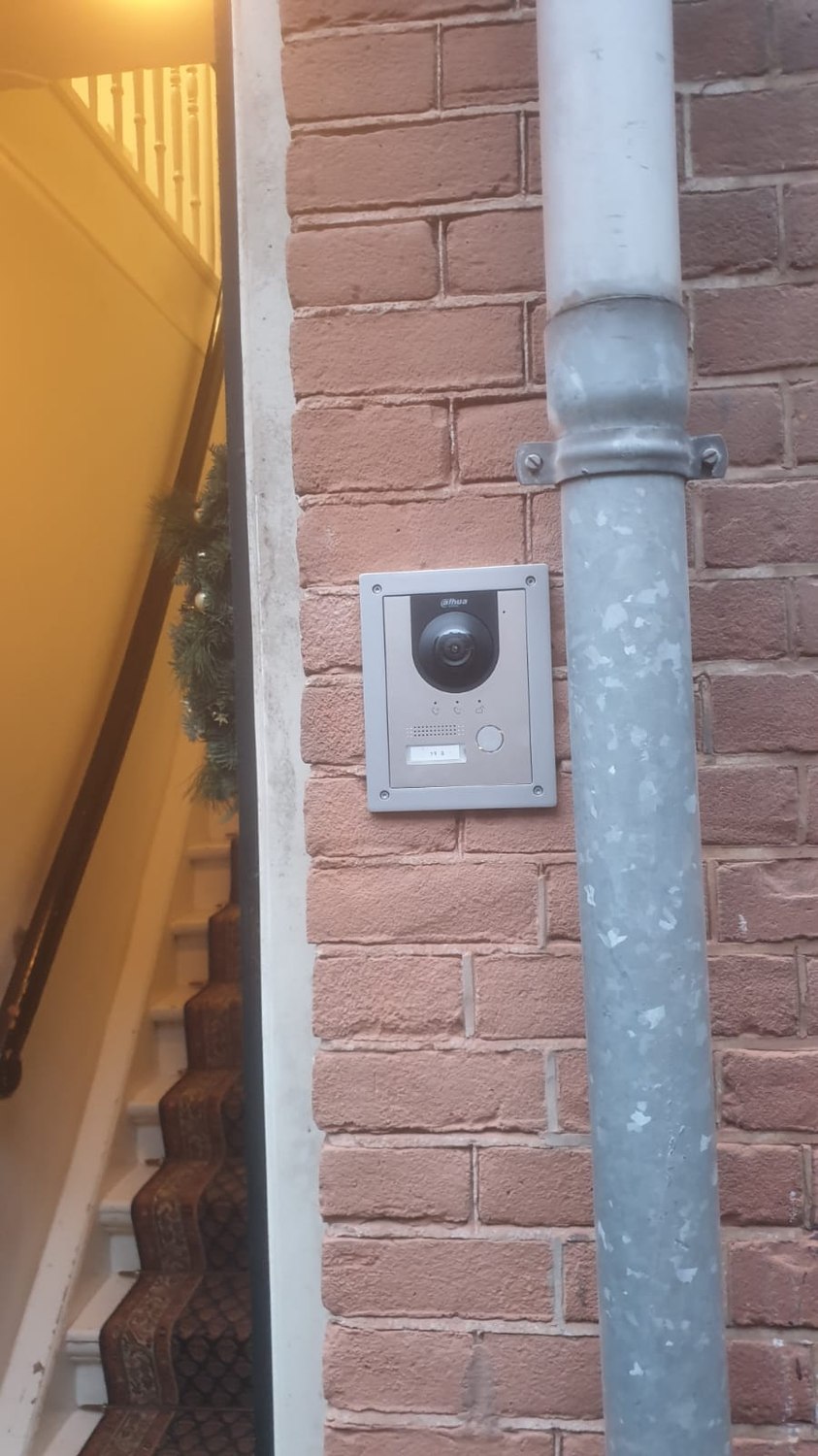 Monteur van CameraInstallatie werkt een intercom- en toegangsinstallatie af bij de entree