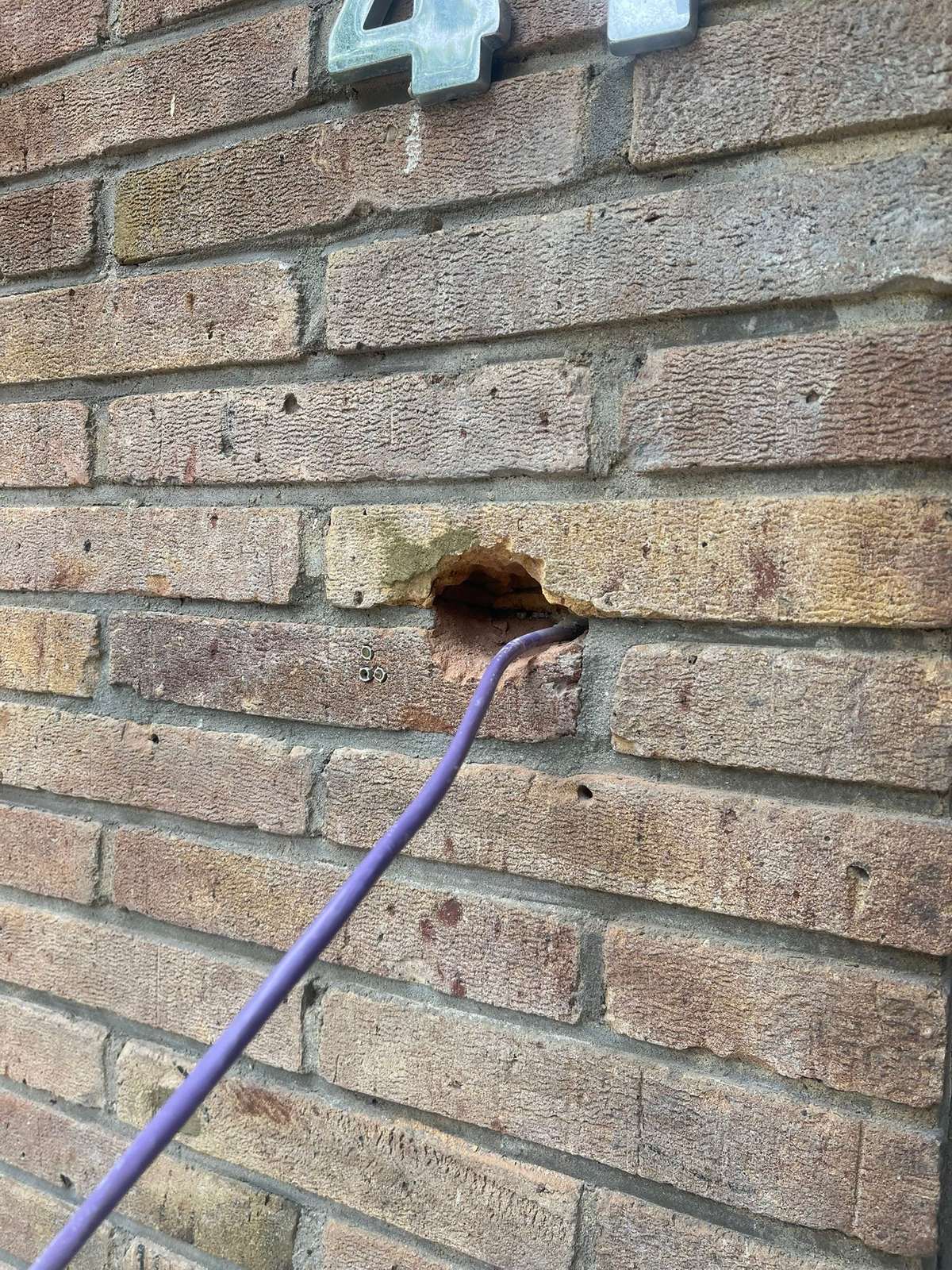Netwerkkabel komt door een strak geboord gat in de bakstenen muur naar buiten