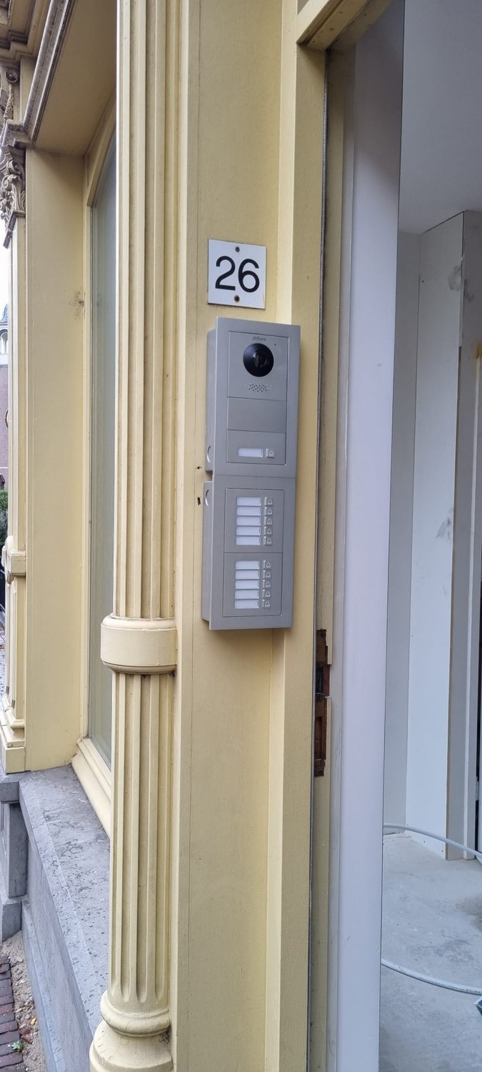Modulair intercompaneel met camera en twee rijen beldrukkers, ingebouwd naast de entreedeur van een appartementengebouw