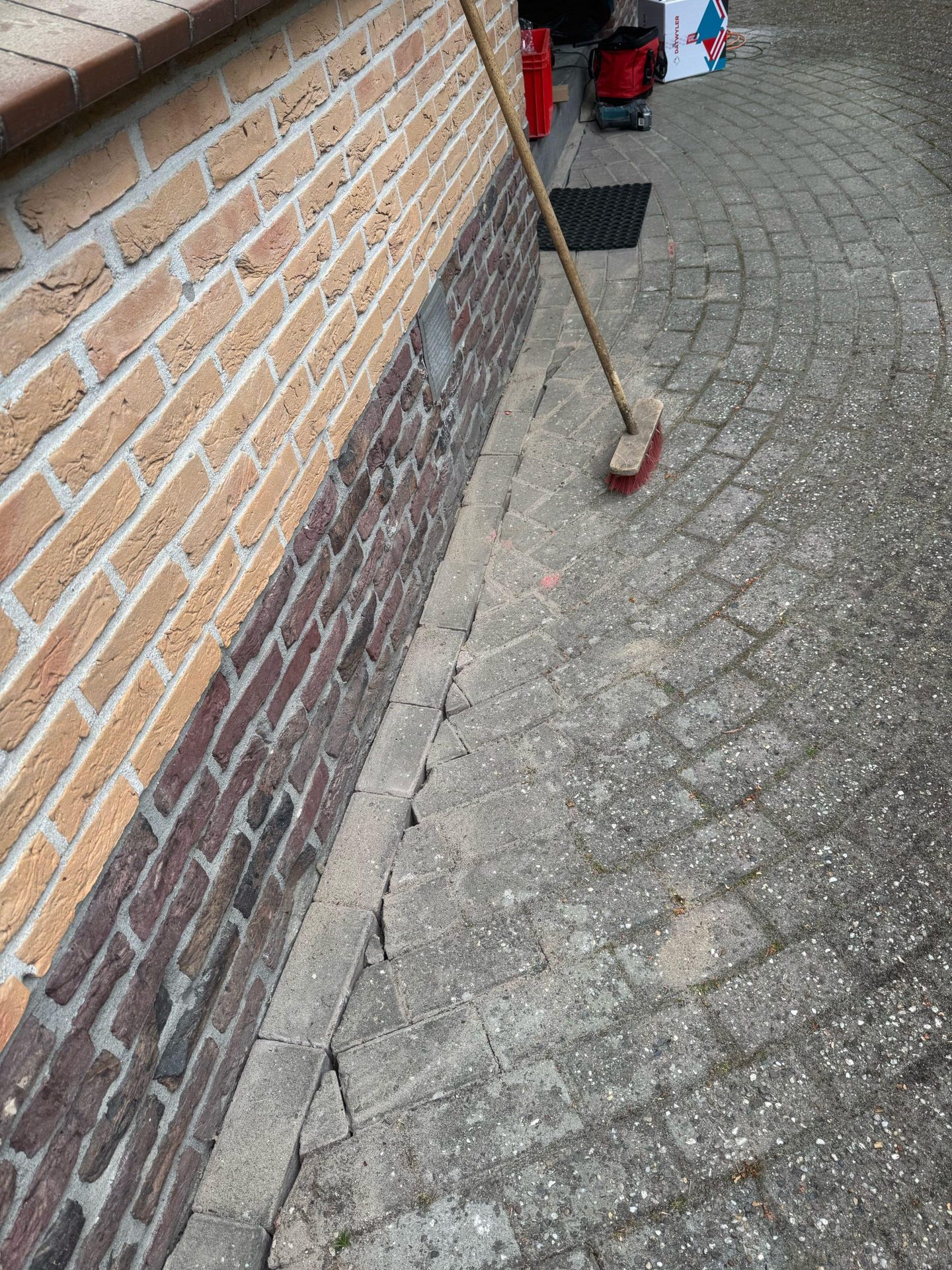 Sleuf in de bestrating langs de gevel voor de camerakabel, daarna weer dichtgelegd