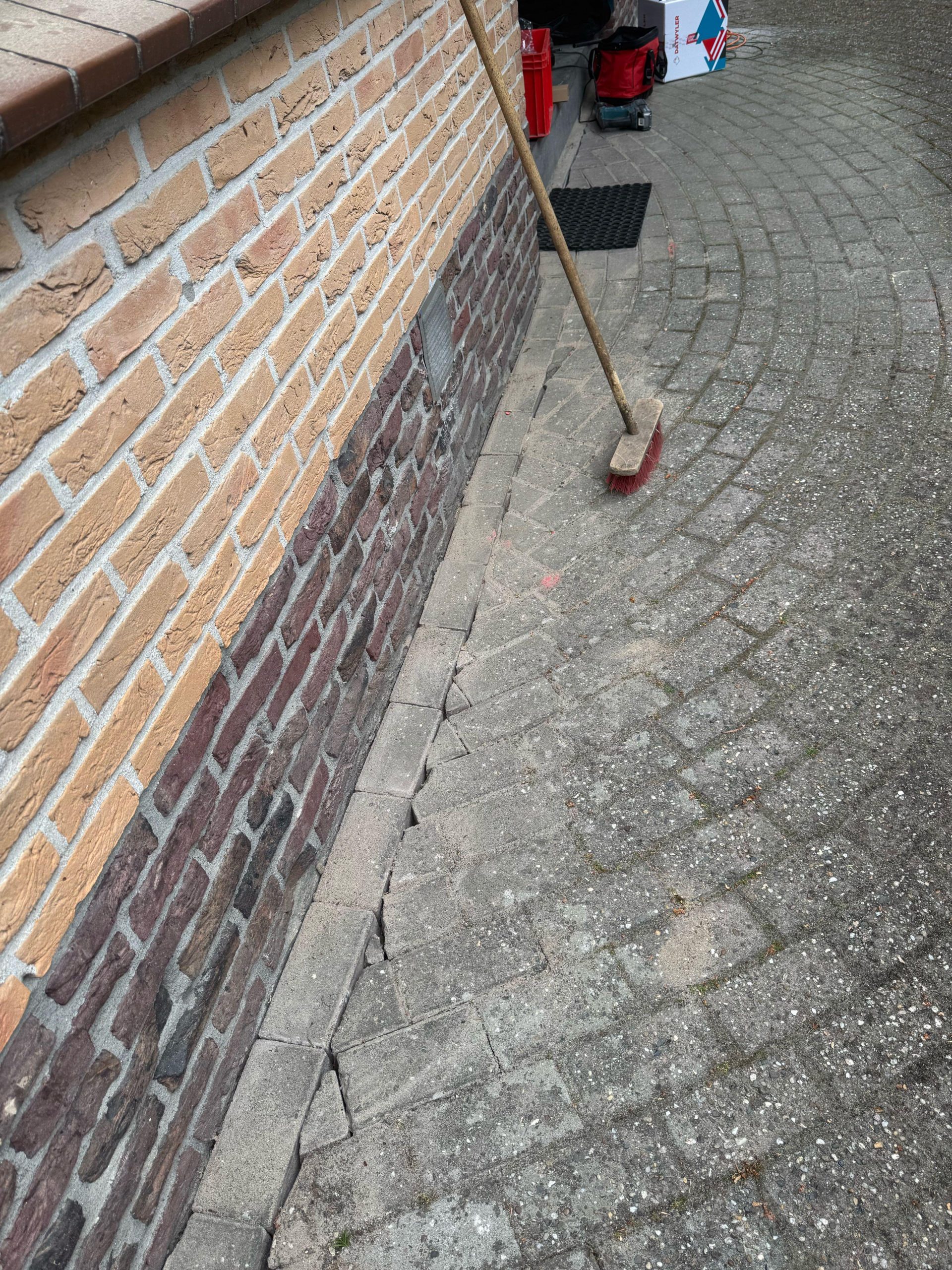 Bestrating langs de gevel opengelegd voor de kabelsleuf, daarna weer netjes teruggelegd