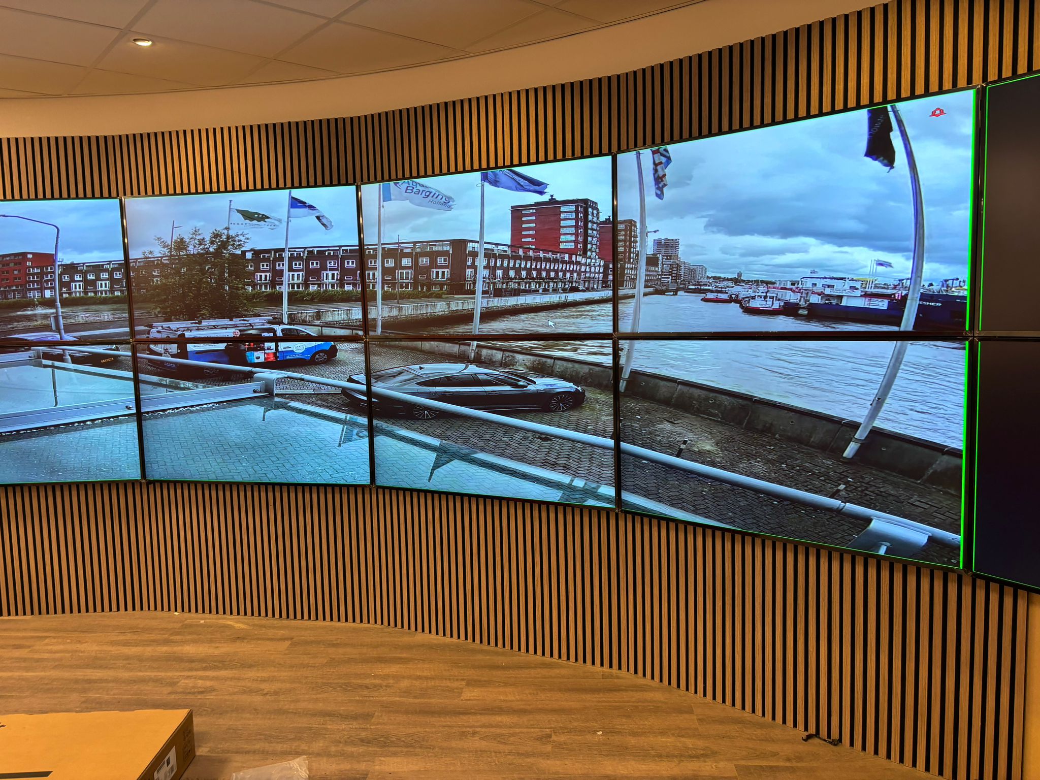 Grote gebogen videowand met een raster aan schermen die live camerabeelden van een locatie tonen, voor centraal meekijken