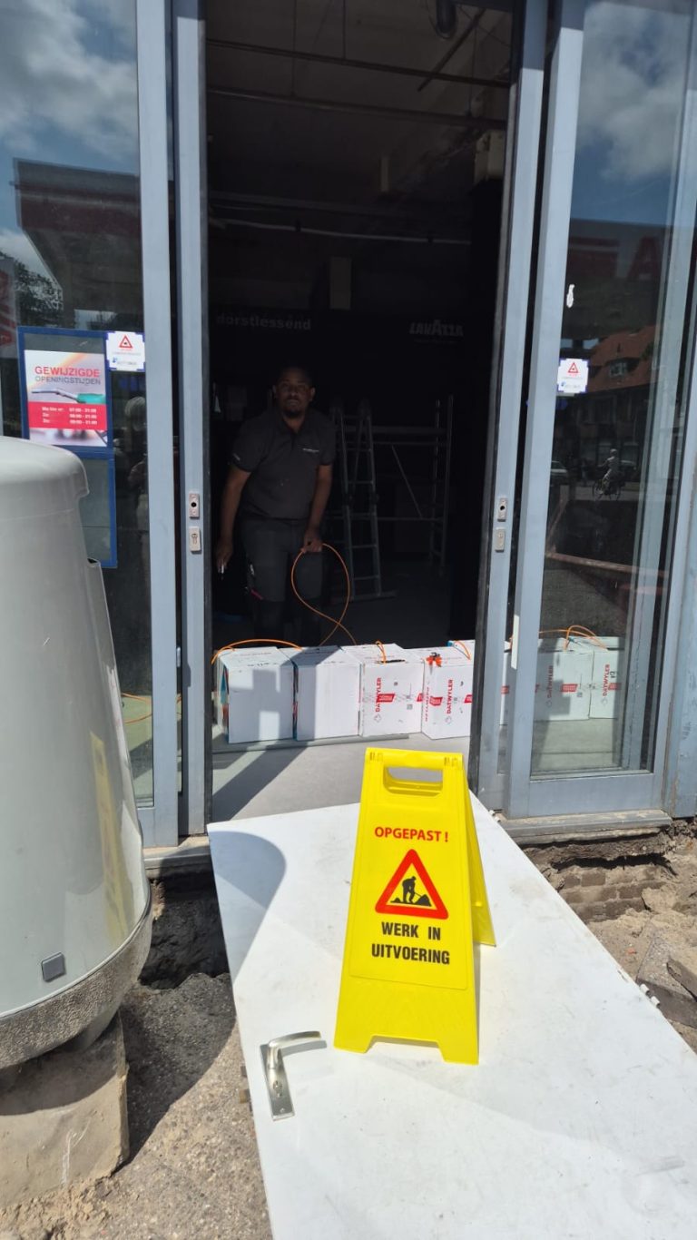 Monteur van CameraInstallatie werkt aan een camera bij de entree van een gebouw