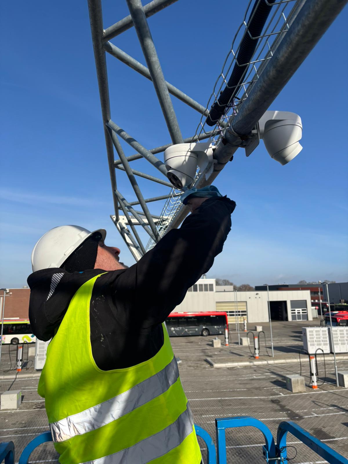 Monteur bevestigt vanuit de hoogwerker een camera aan een stalen mast